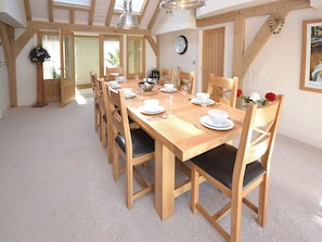 Comedor con una mesa de madera dispuesta para seis personas, rodeada de seis sillas de madera con cojines negros.