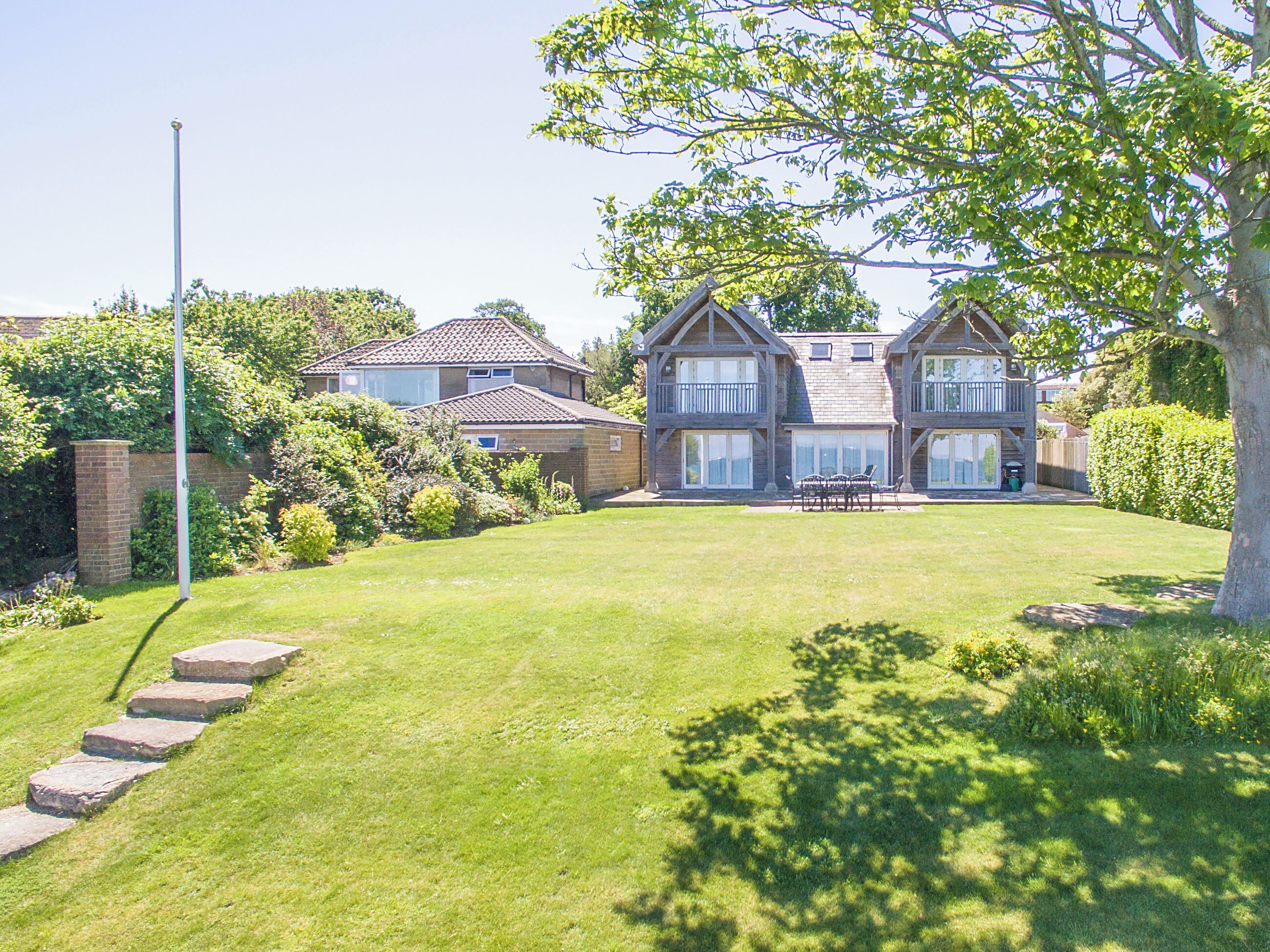 A two-story house with a well-maintained lawn and a patio area with outdoor furniture.