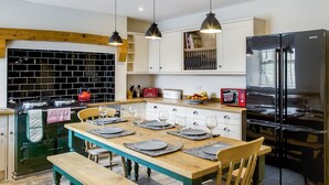 Een moderne keuken met een houten keukeneiland, hanglampen en een zwarte koelkast.