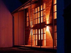 A building with large windows and a wooden facade at night.