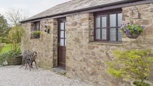 A stone building with a dark brown door, windows with frosted glass, and a hanging flower basket. - 1 bedroom accommodation in Pelynt, near Looe (Pelynt, near Looe)