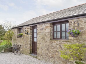 A stone building with a dark brown door, windows with frosted glass, and a hanging flower basket. - 1 bedroom accommodation in Pelynt, near Looe (Pelynt, near Looe)