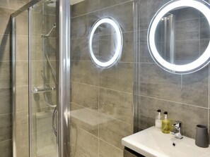 A modern bathroom with a glass-enclosed shower, a vanity with a mirror, and two illuminated mirrors. - Room Apart 2-UKC2335 (Plymouth)