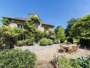 Een stenen huis met een tuinpatio en buitenplaatsing.