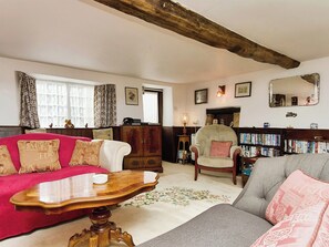 A cozy living room with a red sofa, a grey sofa, a wooden coffee table, and a bookshelf filled with books.
