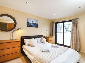 A neatly arranged bedroom with a bed, bedside tables, a mirror, and a painting on the wall. - 1 bedroom accommodation in Cowes (Cowes)
