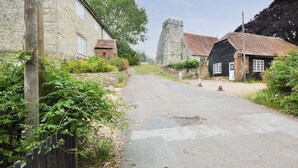 Une étroite route de village bordée de bâtiments en pierre, d’une clôture en bois et d’une tour.