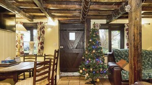 Un intérieur rustique avec une table à manger en bois, des chaises, un sapin de Noël et un canapé en cuir.