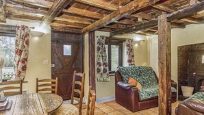 Un intérieur rustique avec un plafond en bois, une table à manger entourée de chaises, un canapé et une cheminée.