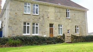 Un bâtiment en pierre à deux étages, doté d’un toit recouvert de tuiles, de nombreuses fenêtres et d’une porte d’entrée.