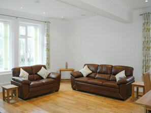 A spacious living room with two brown leather sofas, a wooden coffee table, and a small wooden side table. - 2 bedroom accommodation in Shanklin (Shanklin)