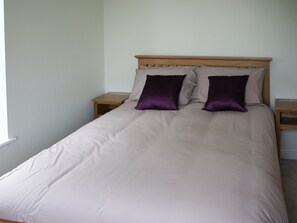A single bed with a wooden headboard, two nightstands, and a window on the left. - Highlands Apartment 2 - UKC2900 (Shanklin)