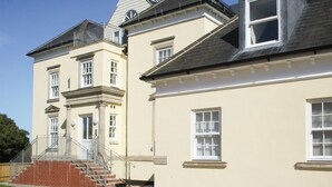 Un edificio a due piani con una facciata simmetrica, un ingresso centrale con una scalinata e un piccolo balcone al secondo piano.