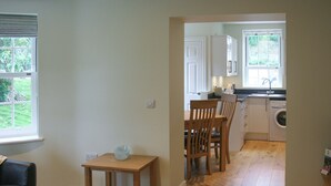 Una cucina con zona pranzo, pavimento in legno e vista sull'esterno.