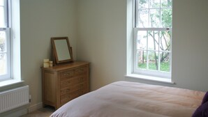 Una camera da letto con un letto, una cassettiera e due finestre.