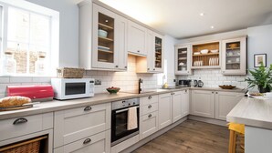 Een moderne keuken met witte kastjes, een magnetron, een broodrooster en een spoelbak.
