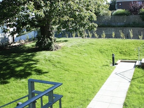 A grassy area with a metal bench and a paved path. - Highlands Apartment 3 - UKC3105 (Shanklin)