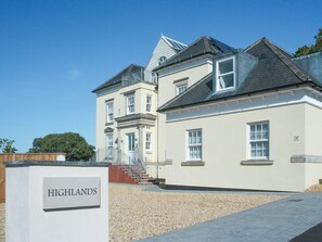 A large, two-story building with a beige facade and a sign reading "HIGHLANDS". - Highlands Apartment 3 - UKC3105 (Shanklin)
