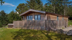 A rustic cabin with a wooden exterior, large windows, and a balcony. - 2 bedroom accommodation in Forres, near Nairn (Forres, near Nairn)