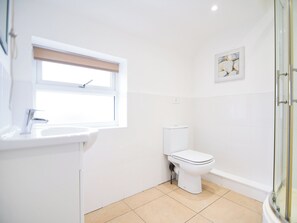 A small, white bathroom with a toilet, sink, and a window. - 3 bedroom accommodation in Murton, near York (Murton, near York)