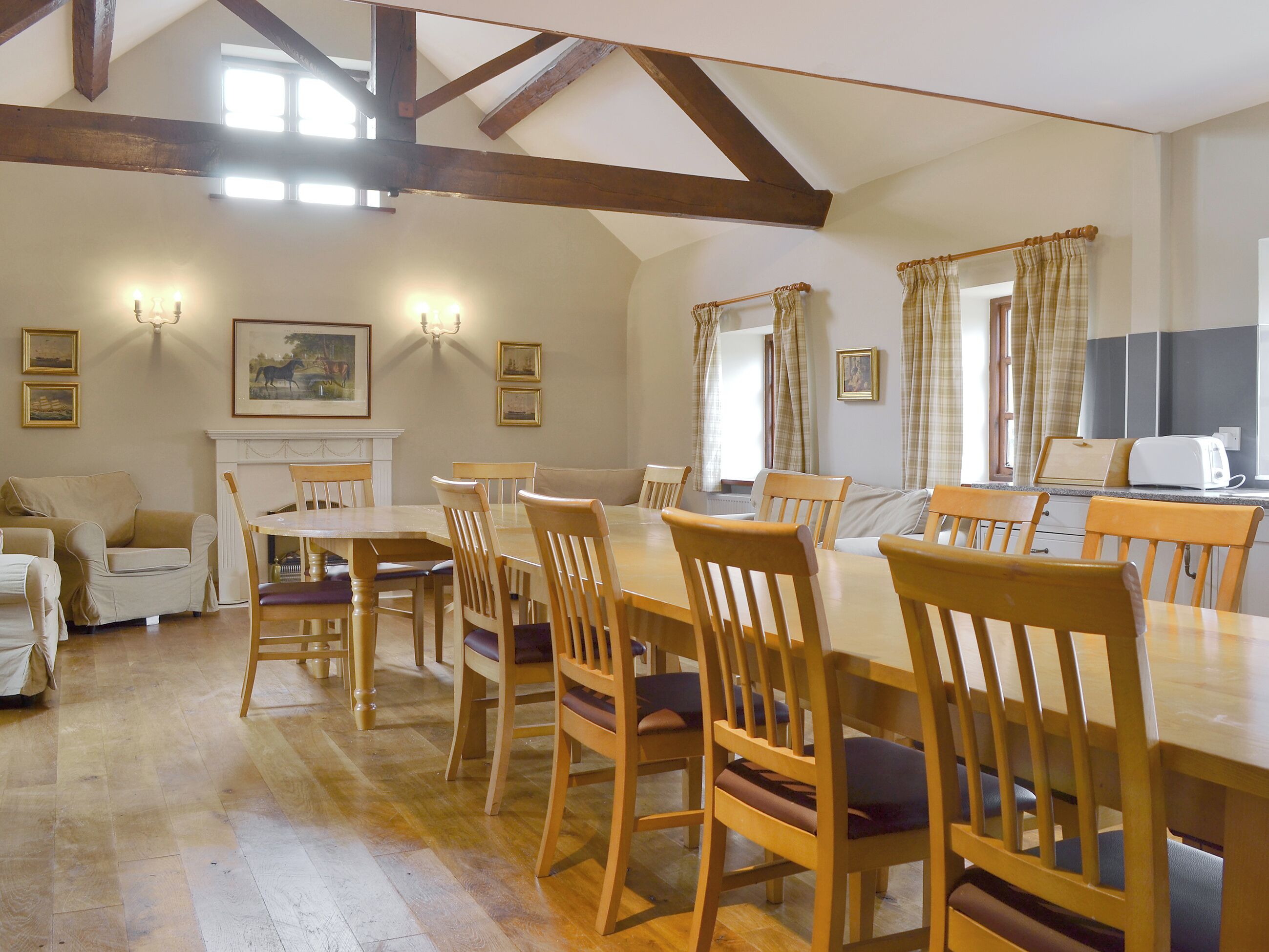A dining area with wooden tables and chairs, a fireplace, and framed artwork on the walls.