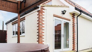 A patio area with a wooden table and a hot tub. - 2 bedroom accommodation in Murton, near York (Murton, near York)
