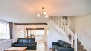 A spacious living room with two black leather sofas, a wooden coffee table, and a staircase with a white railing. - 2 bedroom accommodation in Murton, near York (Murton, near York)
