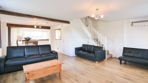 A spacious living room with a wooden floor, a staircase, and a dining area in the background. - 2 bedroom accommodation in Murton, near York (Murton, near York)