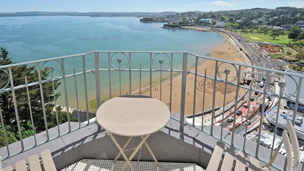 Ein Balkon mit Blick auf einen Strand und eine Küstenstadt.