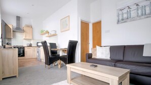Ein modernes Wohnzimmer mit einer Couch, einem Couchtisch und einem Essbereich mit Stühlen und einem Tisch.