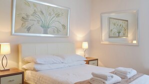A hotel room with a bed, two bedside tables, a drawer unit, and two wall-mounted lamps. - 2 bedroom accommodation in Torquay (Torquay)
