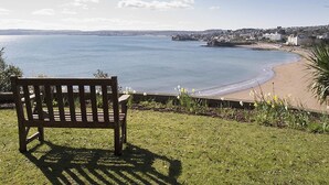 A bench overlooking a beach with a view of the sea and distant buildings. - 2 bedroom accommodation in Torquay (Torquay)