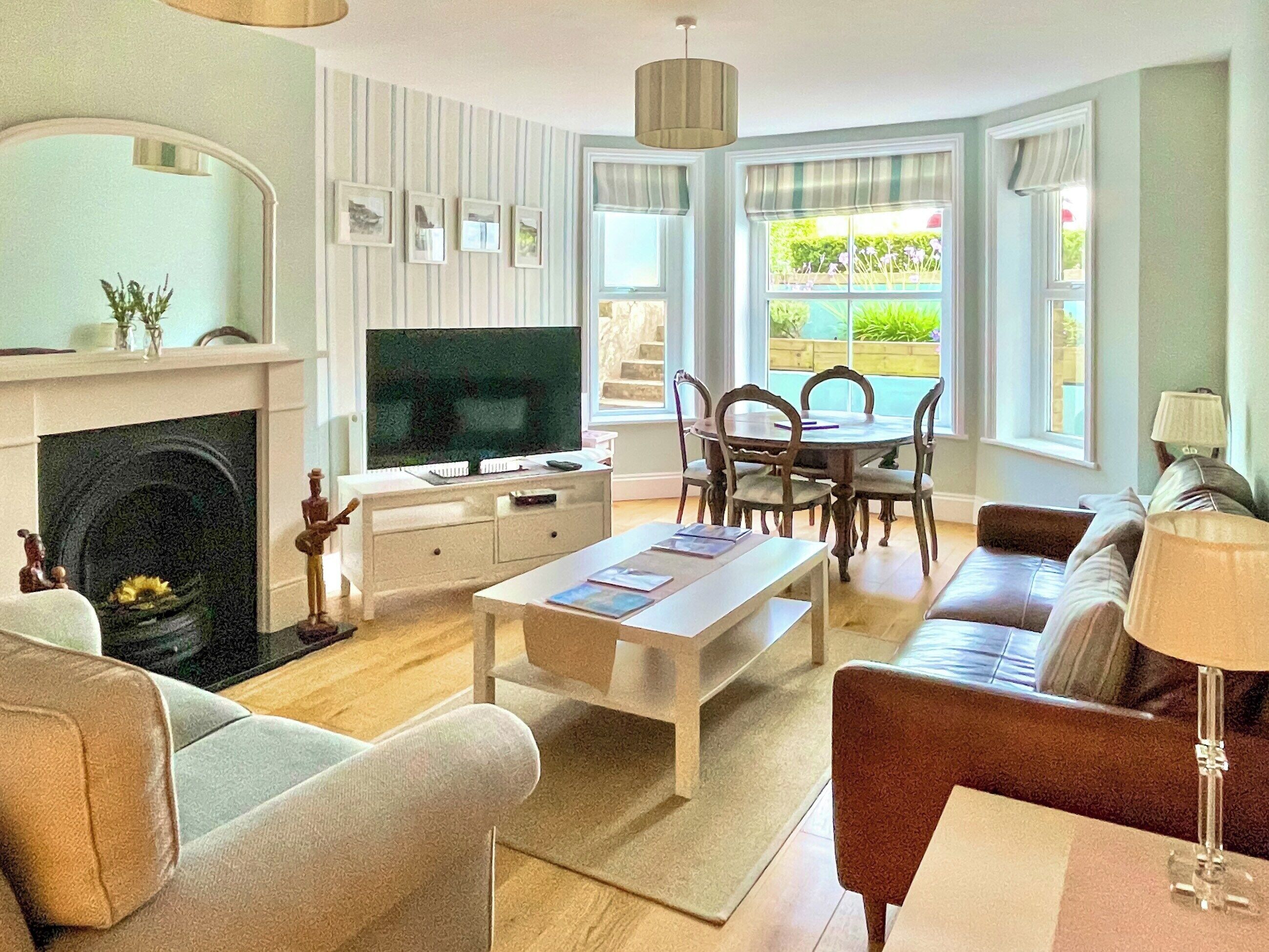 Ein Wohnzimmer mit Kamin, Fernseher, Esstisch und Sitzecke.