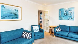 A room with two blue sofas, a small round table, and a door leading to another room. - 3 bedroom accommodation in Ventnor (Ventnor)