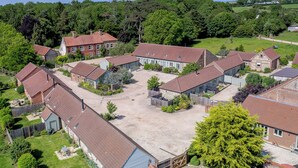 Un quartier résidentiel composé de plusieurs maisons, chacune dotée d’un toit recouvert de tuiles rouges, et entouré de verdure et d’arbres.