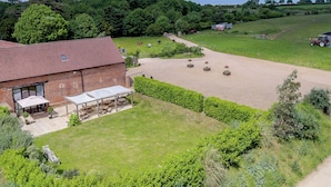 A rural farmstead with a brick barn, outdoor seating area, and a fenced horse paddock. - The Old Feedhouse - UKC3679 (Tattersett, near Fakenham)