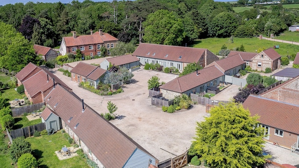 A residential area with multiple houses, each with a red-tiled roof, surrounded by greenery and trees. - The Old Feedhouse - UKC3679 (Tattersett, near Fakenham)