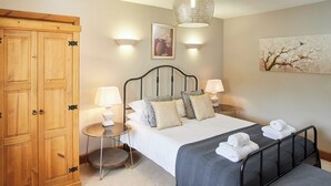A bedroom with a bed, bedside tables, a wardrobe, and a hanging light fixture. - The Old Feedhouse - UKC3679 (Tattersett, near Fakenham)