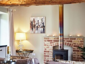 Una habitación acogedora con chimenea de ladrillo, una mesa con lámpara y un cuadro en la pared.