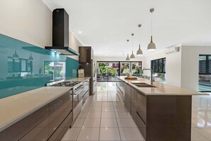 A modern kitchen with a central island, stainless steel appliances, and pendant lighting. - Belle Escapes Sandcastles (Palm Cove)