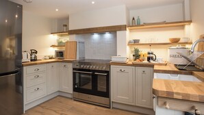 A modern kitchen with a stainless steel refrigerator, a built-in oven, and a wooden countertop. - 3 bedroom accommodation in Worstead, near North Walsham (Worstead, near North Walsham)