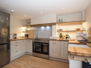 Eine moderne Küche mit einem Edelstahl-Kühlschrank, einem eingebauten Ofen und einer Holz Arbeitsplatte.