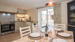 A modern kitchen with a dining area, featuring a built-in oven, a stainless steel range, and a dining table set for four. - 3 bedroom accommodation in Worstead, near North Walsham (Worstead, near North Walsham)