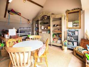 A cozy room with a wooden table, chairs, a bookshelf, and a mirror.
