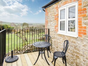 Een balkon met uitzicht over het landschap, een tafel en twee stoelen.