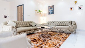 Ein modernes Wohnzimmer mit einer Eckcouch, einem runden Couchtisch und einem gemusterten Teppich.