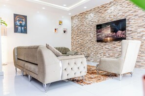 Un salon moderne avec un canapé, un fauteuil et un téléviseur à écran plat fixé sur un mur dont le motif imite un mur de briques.