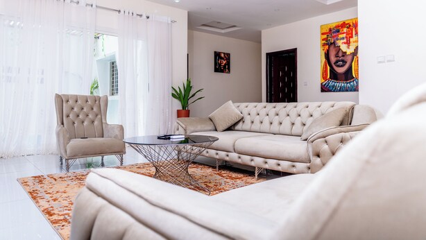 Ein modernes Wohnzimmer mit einem beigen Sofa, einem gepolsterten Sessel und einem Glastisch.