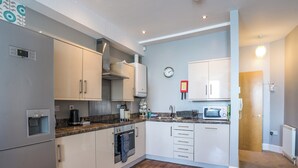 Eine moderne Küche mit weißen Schränken, einem Edelstahlkühlschrank, einem eingebauten Backofen und einer Mikrowelle.