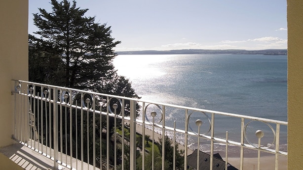 A balcony with a metal railing overlooking a beach and ocean. - 2 bedroom accommodation in Torquay (Torquay)